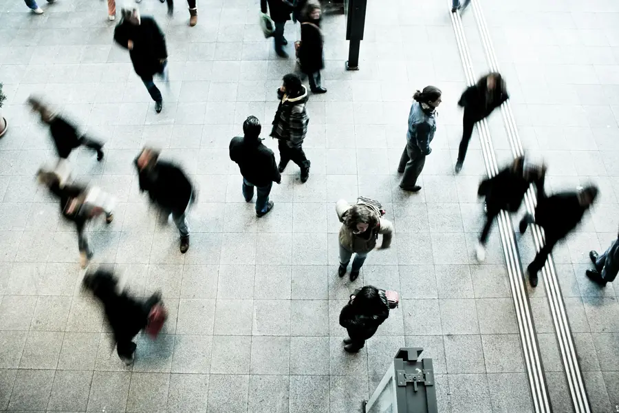 Overhead view of people walking across a busy tiled concourse
