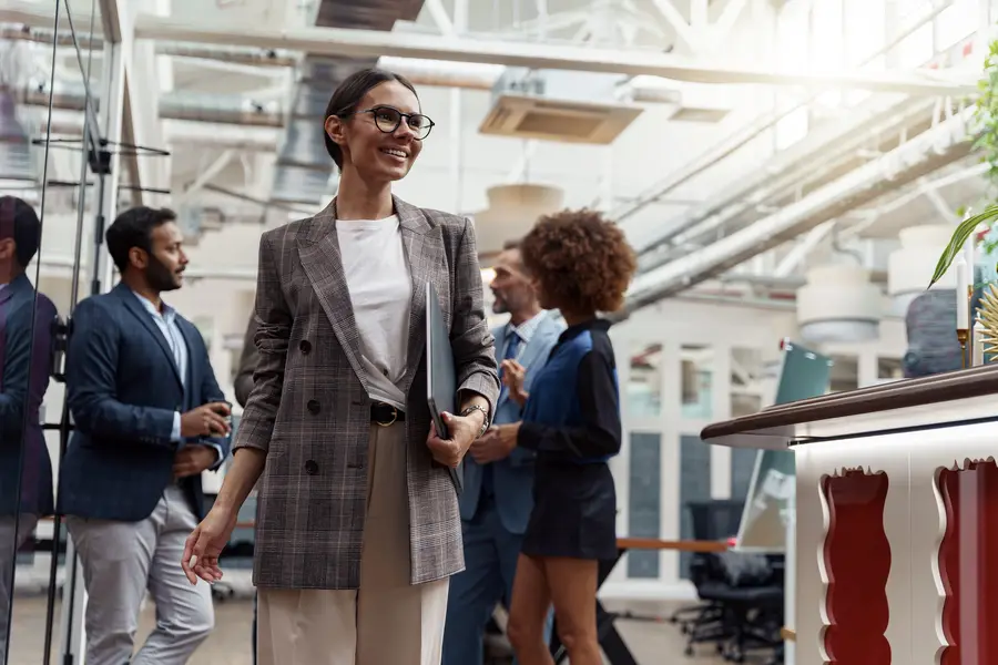 Smiling businesswoman walking through an office with colleagues